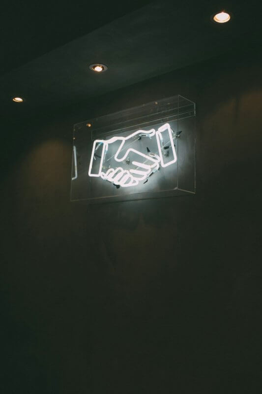 A white neon gas sign of a hand shaked
