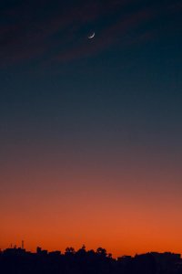 Fiery sunset with crescent moon Crescent moon and fiery orange sunset horizon