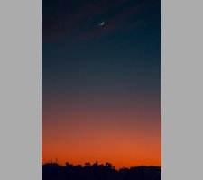 Fiery sunset with crescent moon Crescent moon and fiery orange sunset horizon
